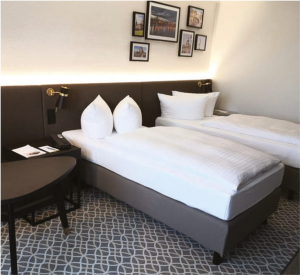 Dwa łóżka z białą pościelą w pokoju hotelowym